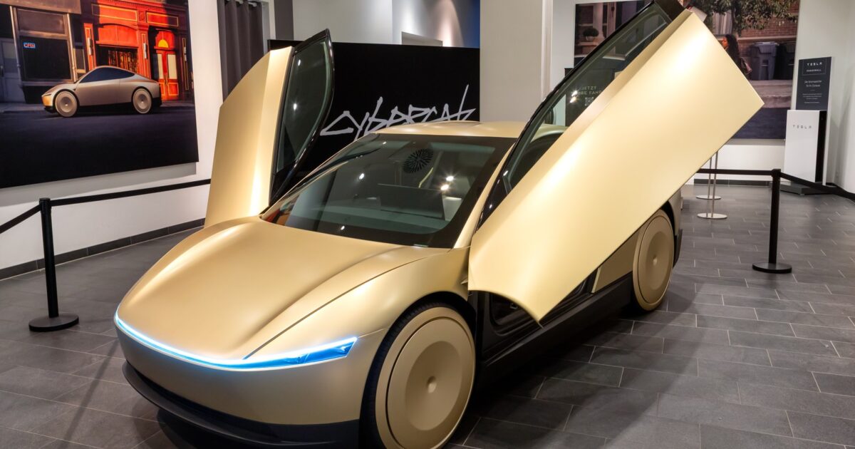 Gold Tesla Cybercab on display with butterfly gull-wing doors open in a Tesla showroom in Berlin