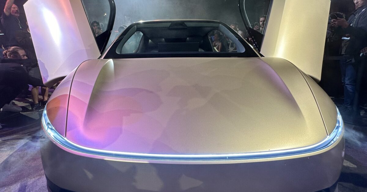 Tesla Cybercab front view with butterfly doors open in gold exterior paint