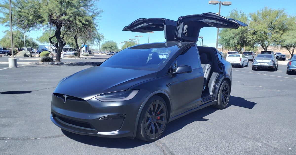 Tesla Model X Plaid with falcon-wing doors open in a parking lot