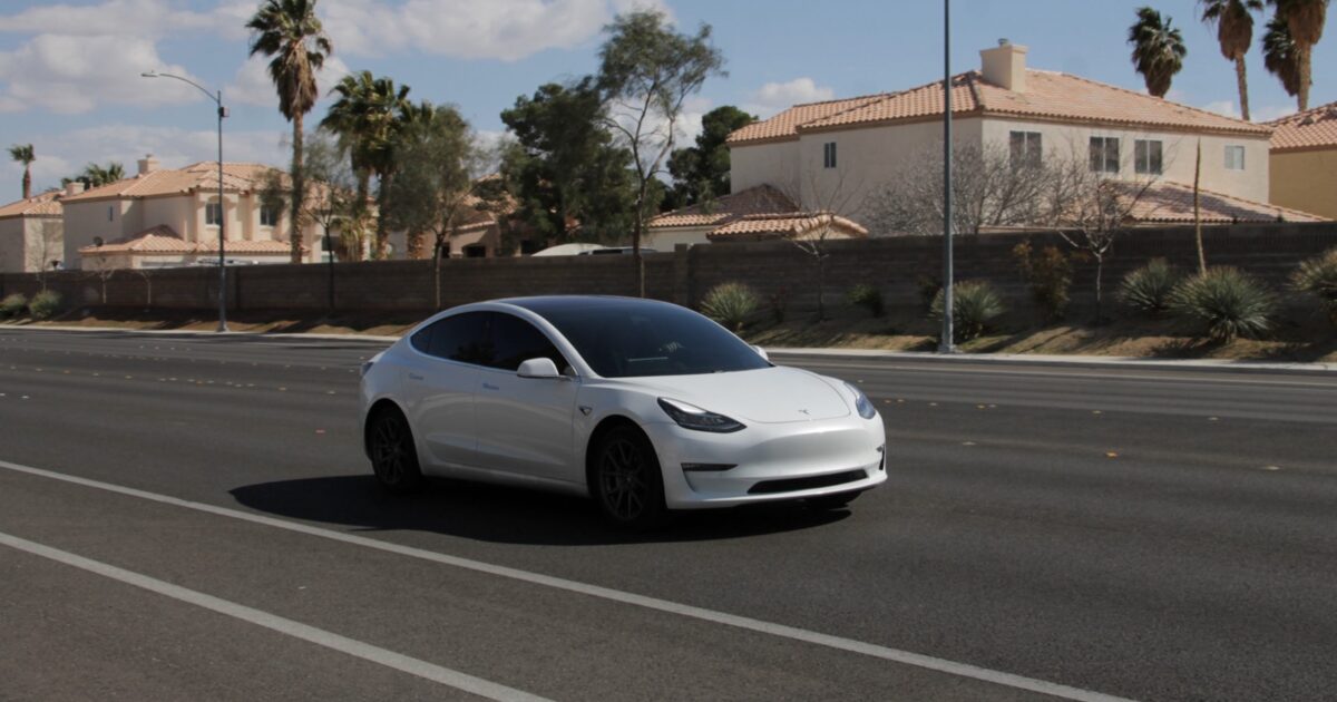 White Tesla Model 3 driving on a road in Las Vegas